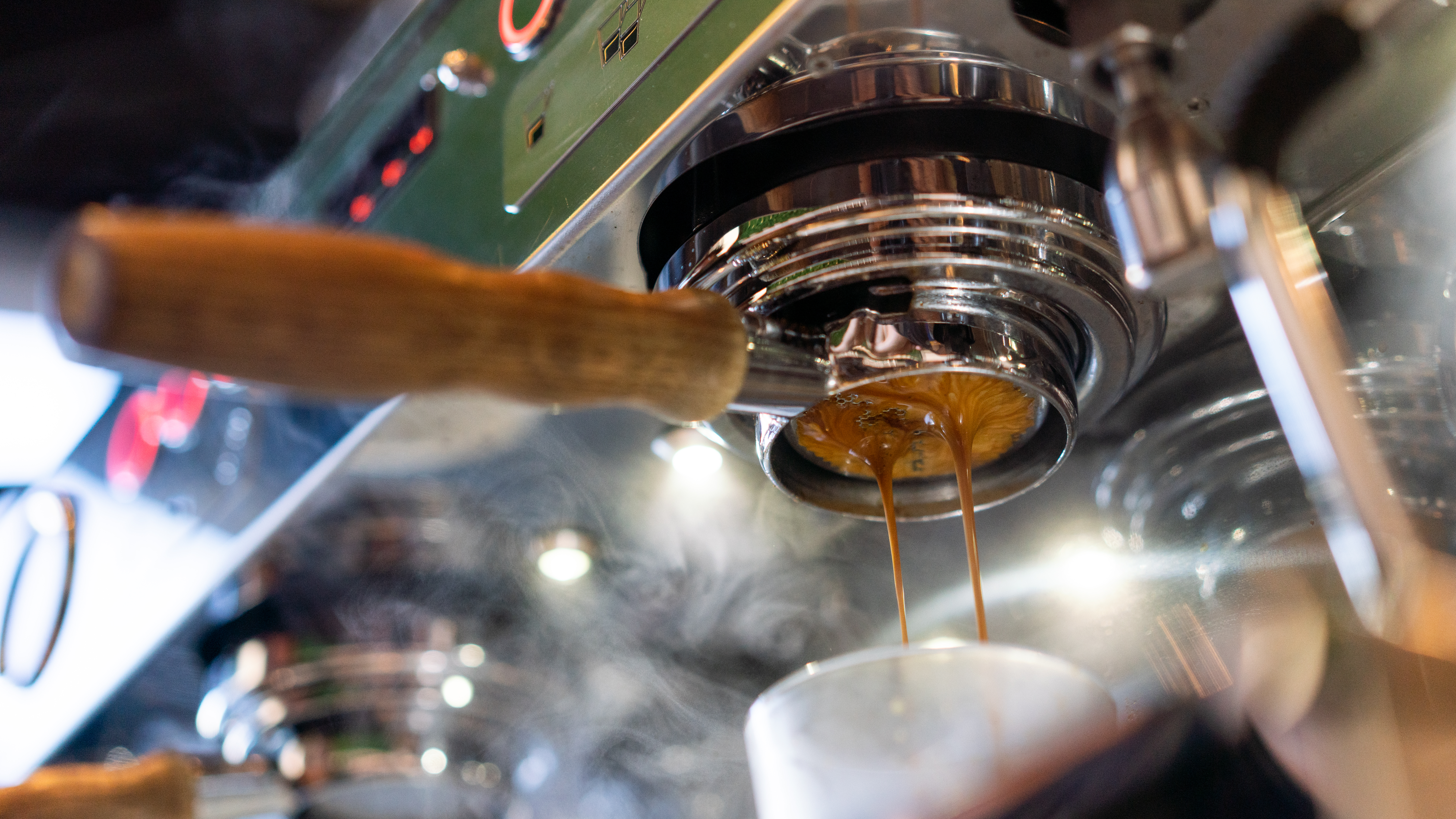 A close-up shot showing a portafilter dispensing freshly brewed espresso into a white cup